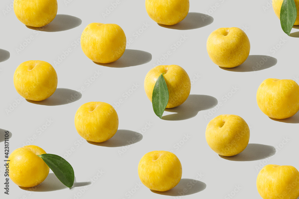Pattern made of fresh yellow plum fruits aligned against ultimate gray background.