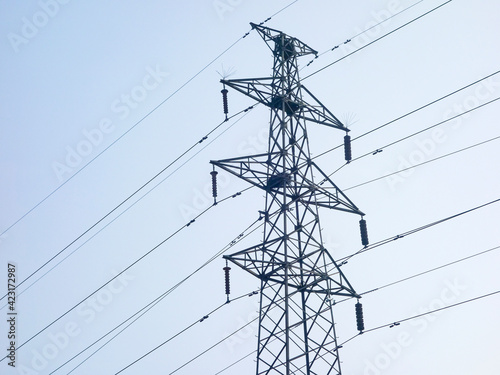 Close up of power poles and towers in the background of blue sky