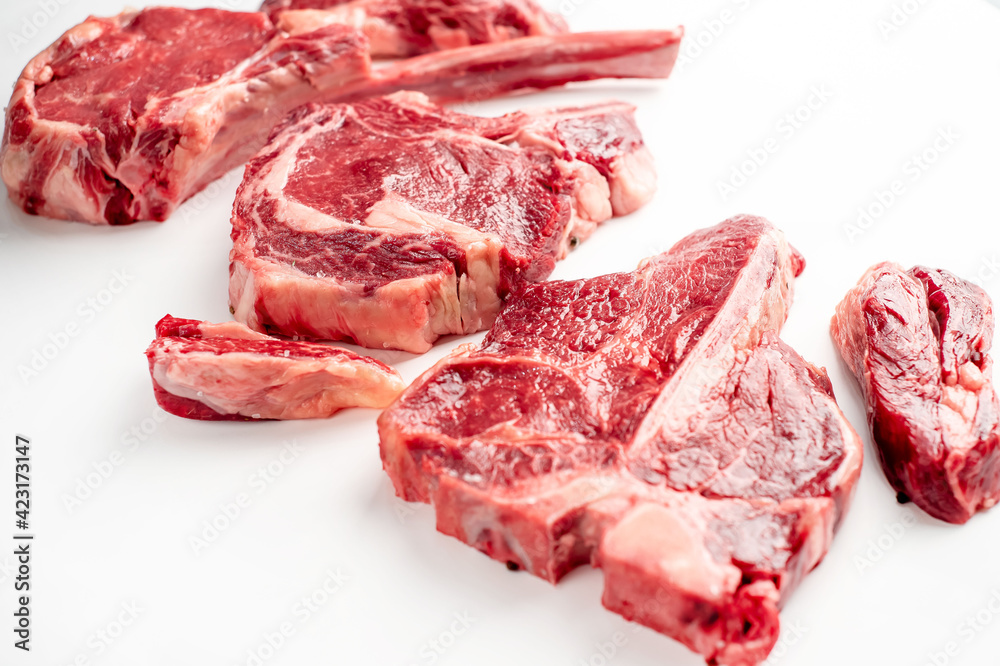 Variety of raw beef steaks on a white background