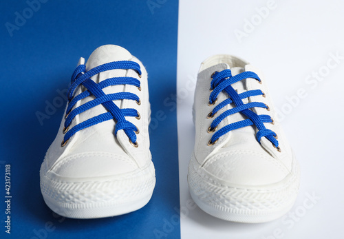 Pair of stylish shoes with blue laces on color background