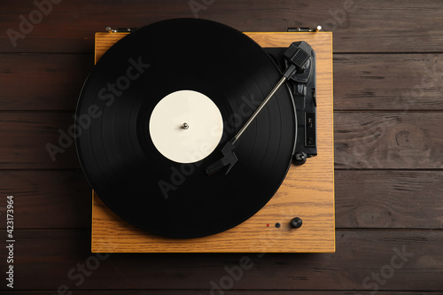 Turntable with vintage vinyl record on wooden background, top view