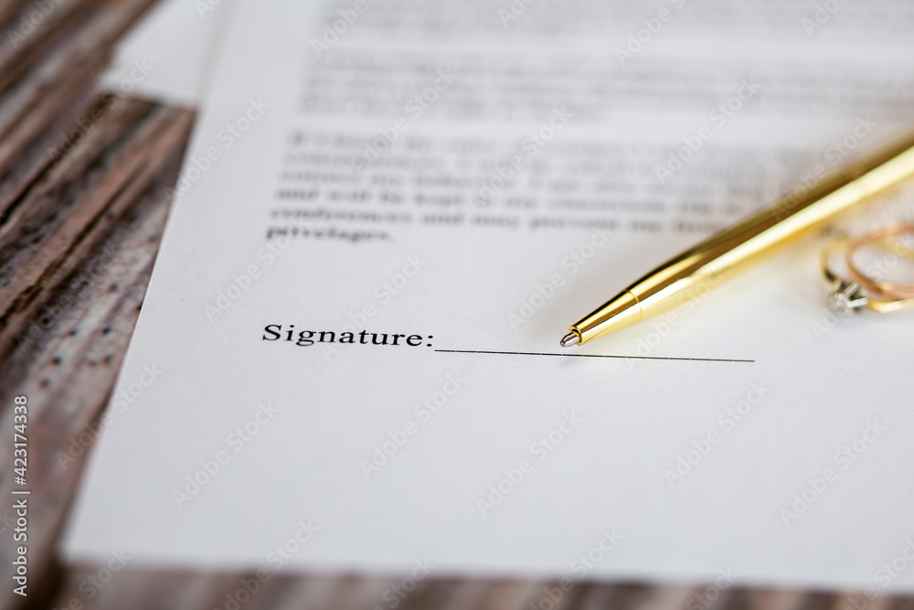 Marriage contract with two golden wedding rings and gold pen