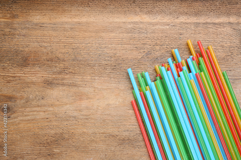 Colorful plastic drinking straws on wooden table, flat lay. Space for text Colorful plastic drinking straws on wooden table, flat lay. Space for text