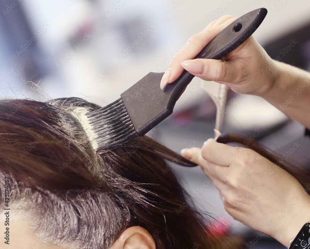 Naklejka premium hairdresser hand with hair dye making haircut and hair coloring on client closeup photo