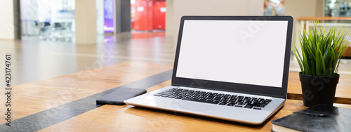 Laptop computer with white blank screen on desk in workspace and copy space concept