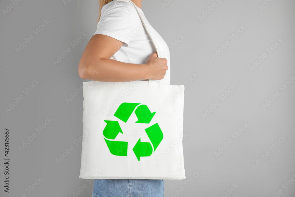 Woman holding bag with recycling symbol on grey background Woman holding bag with recycling symbol on grey background