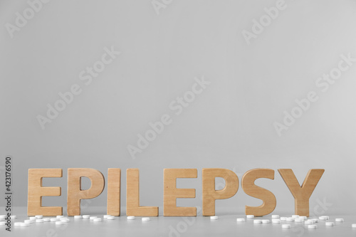 Word Epilepsy made of wooden letters and pills on grey table, space for text