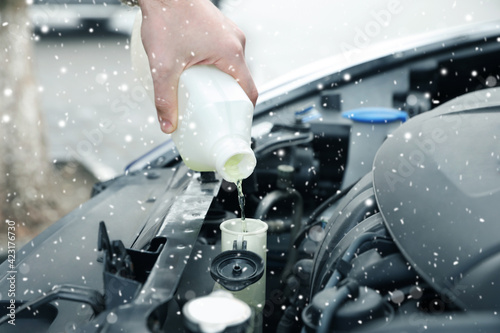 Man filling car radiator with antifreeze outdoors, closeup photo