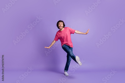 Full length photo of charming cute young guy dressed pink outfit dancing walking isolated purple color background © deagreez
