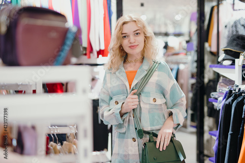 Woman chooses a green bag in the store before buying © antgor