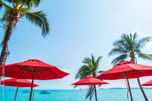 Fototapeta Naklejka Na Ścianę i Meble -  Red umbrella around sea beach ocean with coconut palm tree