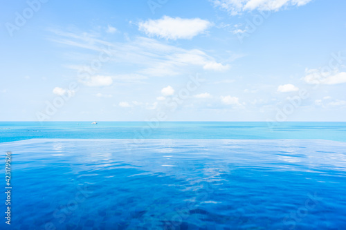 Beautiful infinity outdoor swimming pool with sea ocean view around white cloud blue sky