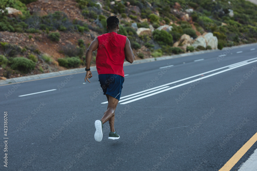 African american man exercising outdoors running on a coastal road