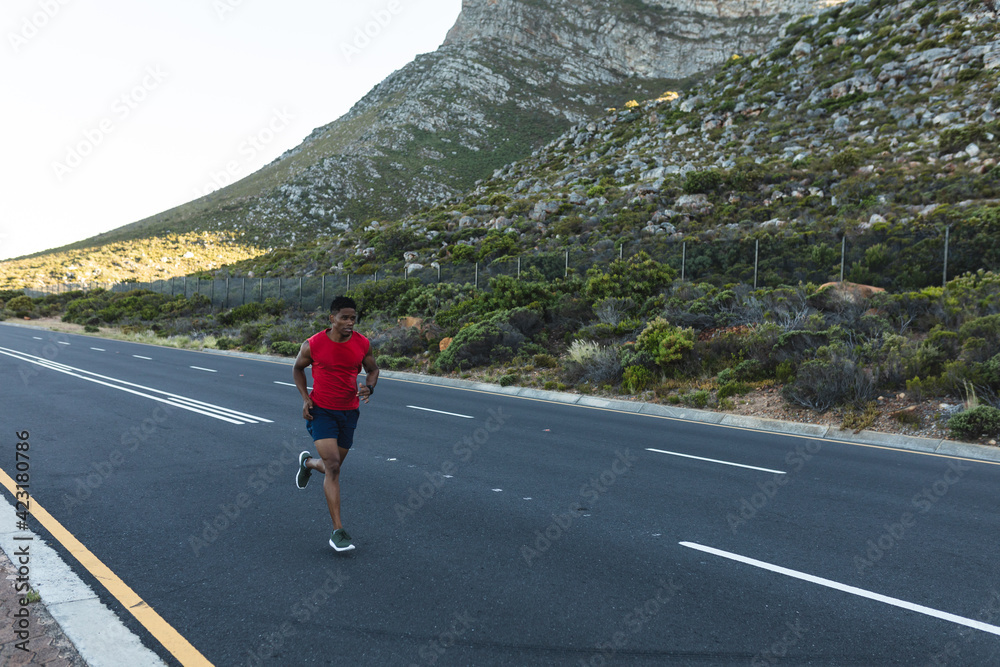 African american man exercising outdoors running on a coastal road African american man exercising outdoors running on a coastal road