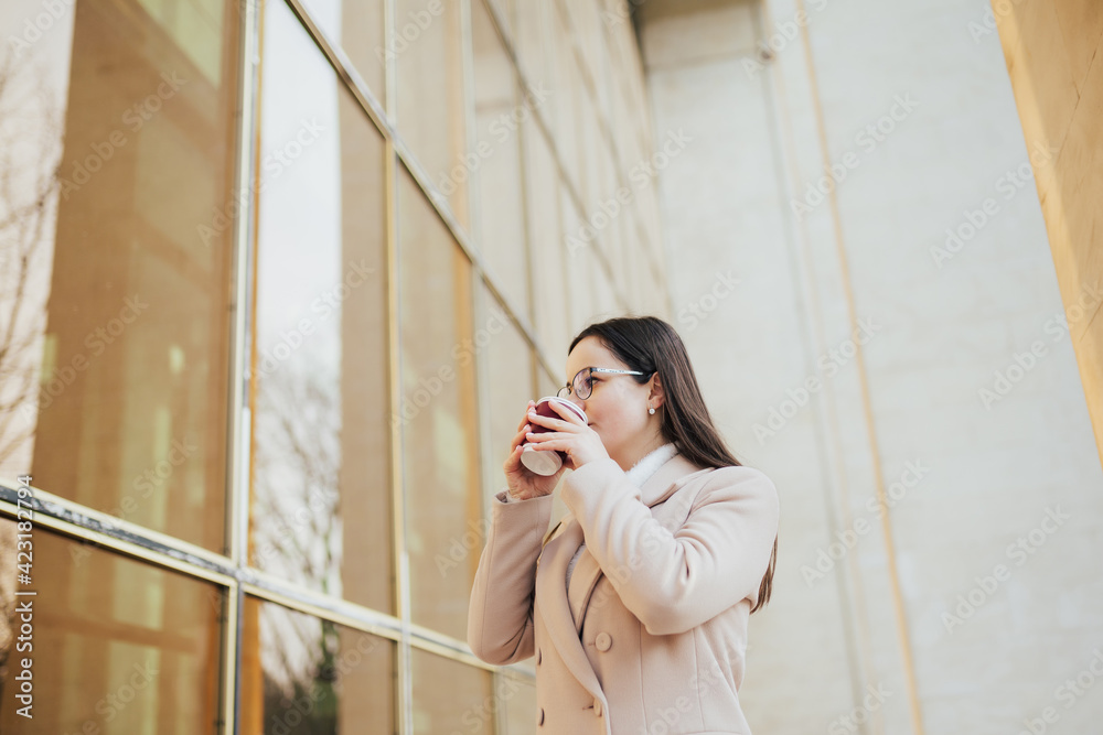 Fototapeta premium Portrait of elegant businesswoman drink the coffee during break time near modern office with panoramic windows.
