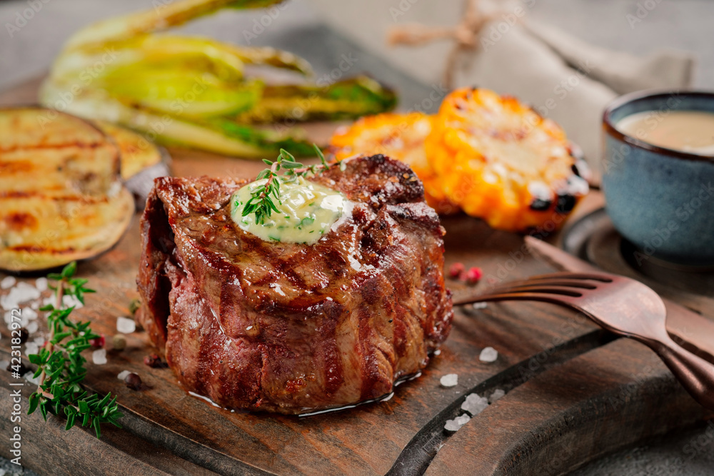 Large grilled Filet Mignon steak with butter and thyme served on a wooden  board. Grilled meat dish with vegetables Stock-foto | Adobe Stock