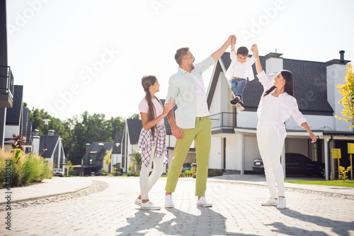 Full length portrait of cheerful full family lady man hands raise boy up have good mood sunny weekend day outdoors