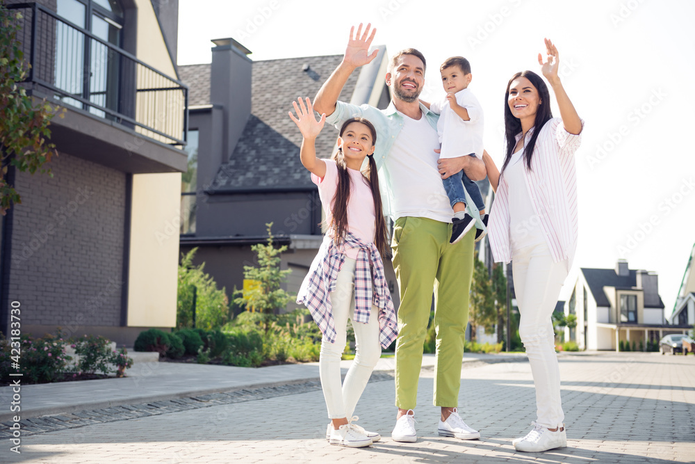Full size photo of young happy positive smiling family waving hands greeting saying hello walk outside outdoors Full size photo of young happy positive smiling family waving hands greeting saying hello walk outside outdoors