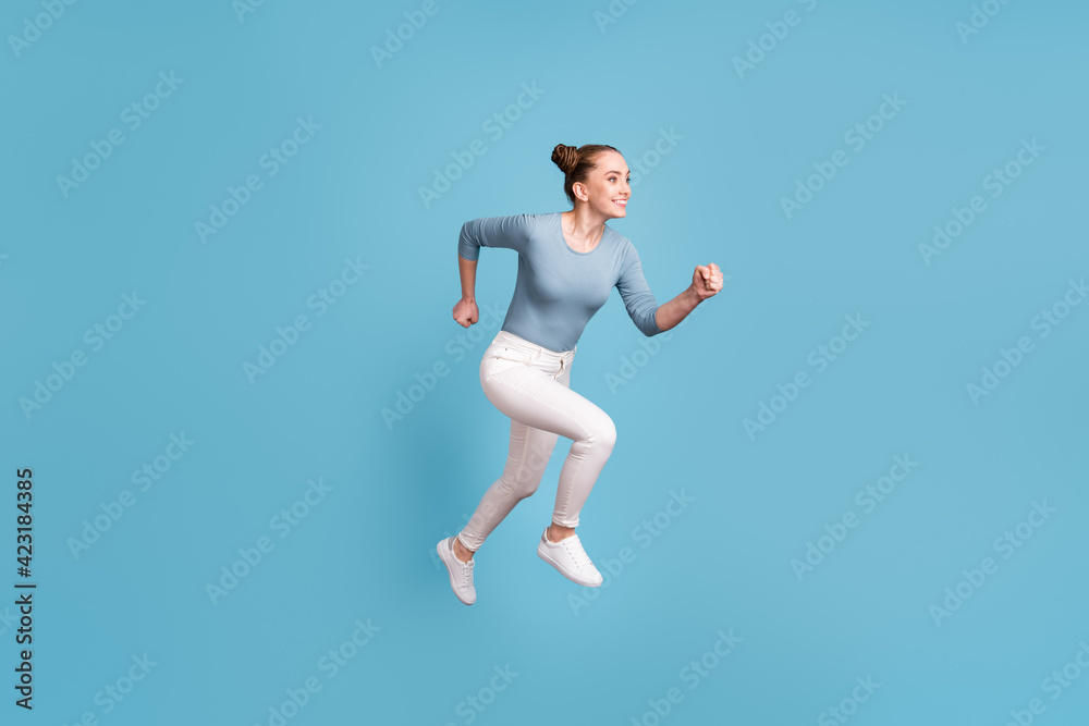 Fototapeta premium Full size profile side photo of teenager cute girl jump run empty space isolated on blue color background