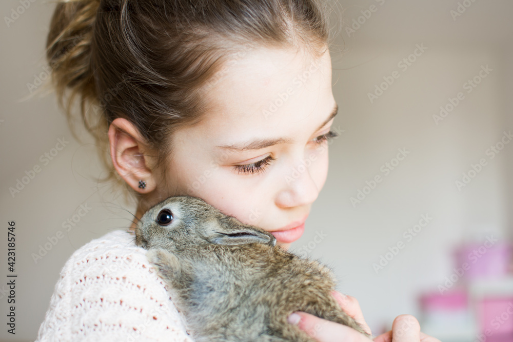 Close-up portrait of young girl with little brown bunny. Symbol of animal care, beauty, love and easter. Close-up portrait of young girl with little brown bunny. Symbol of animal care, beauty, love and easter.