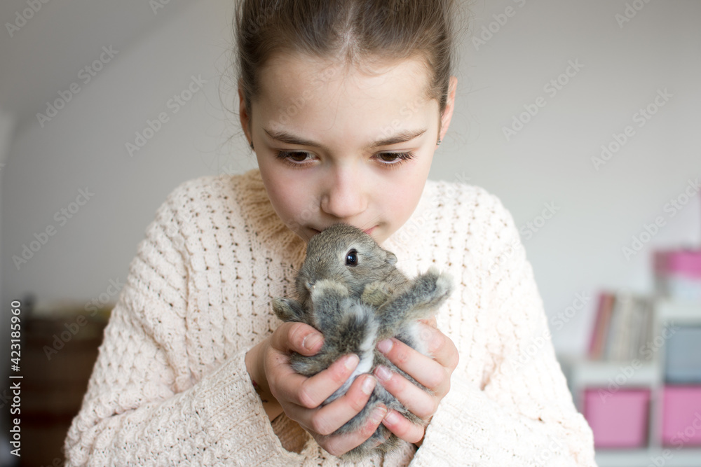 Close-up portrait of young girl kissing little brown bunny. Symbol of animal care, beauty, love and easter. Close-up portrait of young girl kissing little brown bunny. Symbol of animal care, beauty, love and easter.