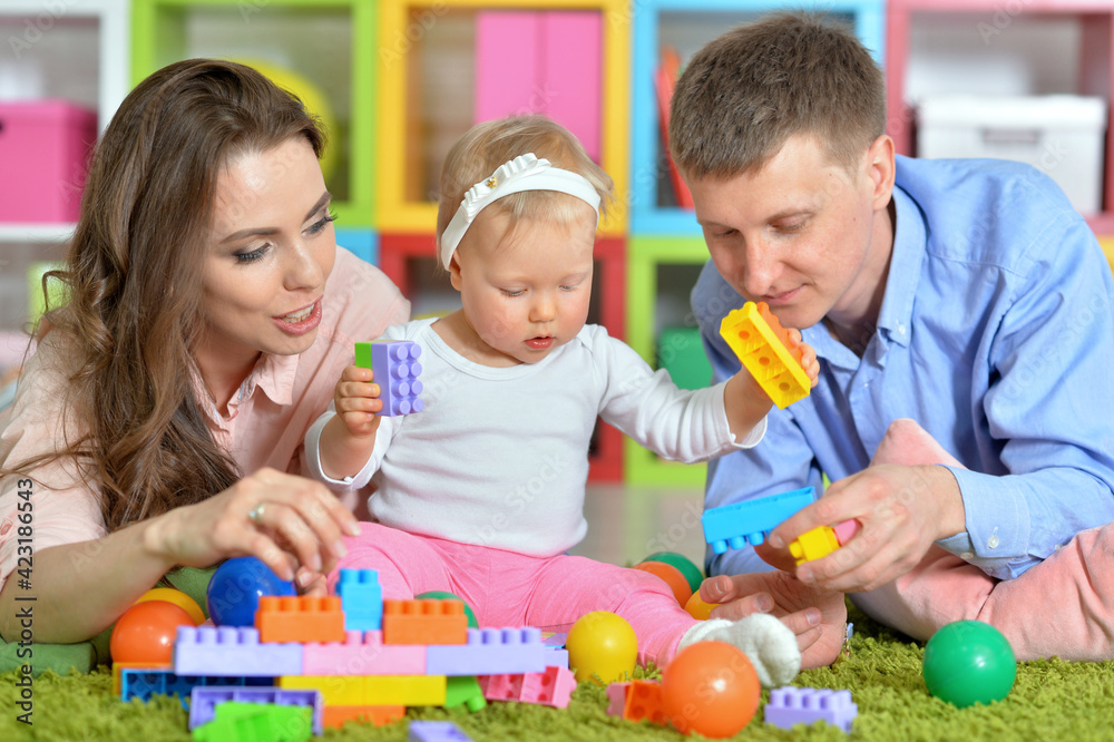 Parents playing with adorable little daughter at playroom Parents playing with adorable little daughter at playroom