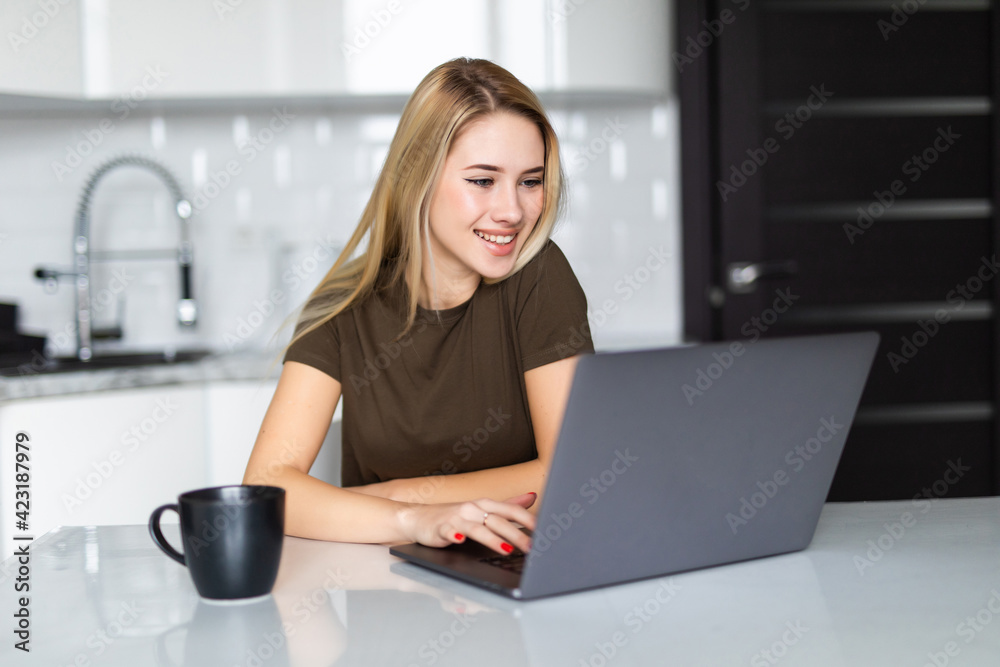 Smiling young woman with coffee cup in the kitchen at home