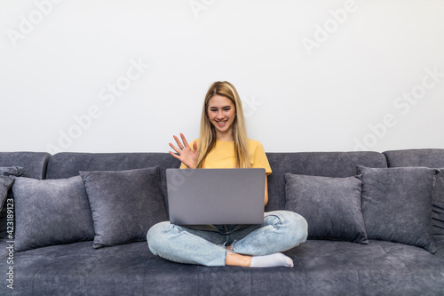 Young happy woman holding video call, gesturing hello to friends, relatives or parents. Attractive female blogger recording new video to followers. Smiling girl having online interview with employer.
