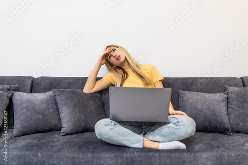 Frustrated sad woman feeling tired worried about problem sitting on sofa with laptop. Stressed depressed girl troubled with reading bad news online, email notification about debt or negative message