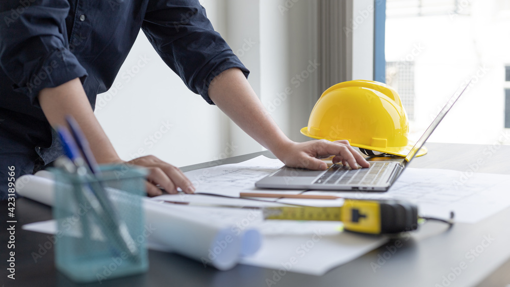Young man with a laptop plotting a system of building structures in ...