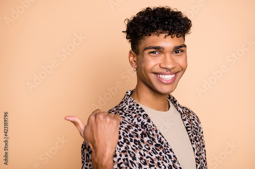 Tableau sur toile Photo of handsome positive dark skin man direct thumb empty space toothy smile i