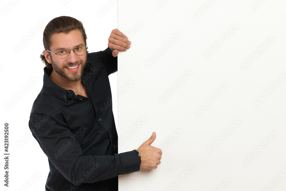 Smiling Man In Black Shirt And Eyeglasses Is Standing Next To Big Banner And Showing Thumb Up Smiling Man In Black Shirt And Eyeglasses Is Standing Next To Big Banner And Showing Thumb Up