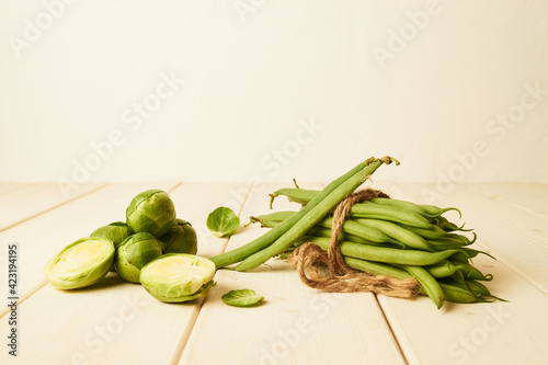 Raw Green beans tied with at string and Brussel sprouts placed on wooden table