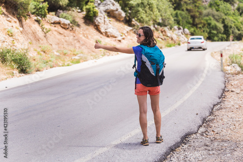 A woman stops a car on the road, a girl hitchhikes