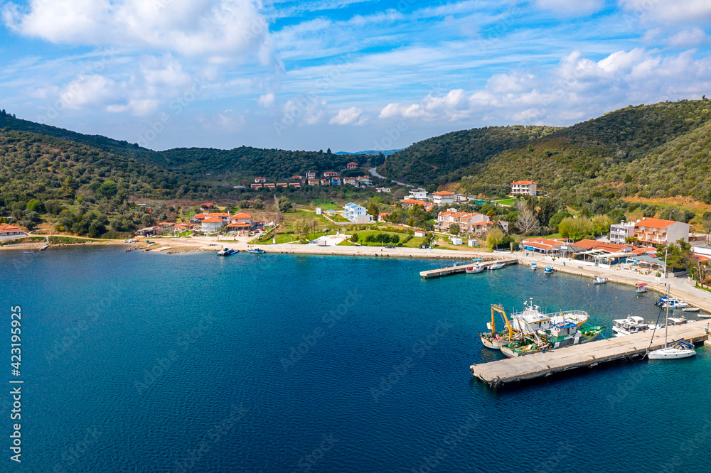 European country village on Mediterranean sea shore with coastline pier for fishing boats. Small resort town on green tree mountains summer background
