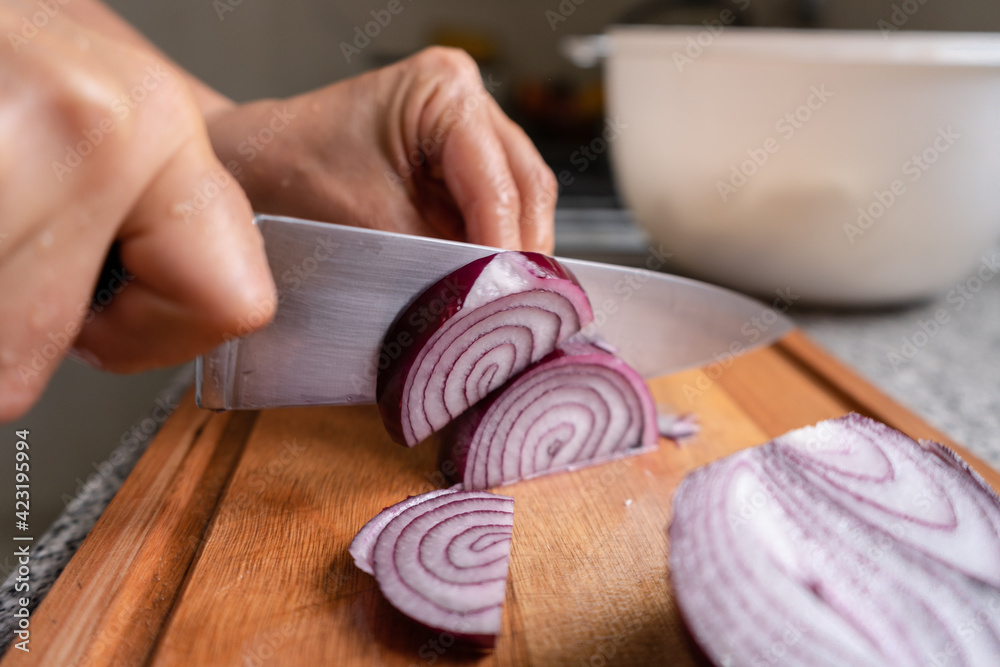 Chef's hands cutting red onion into half thick slices Chef's hands cutting red onion into half thick slices