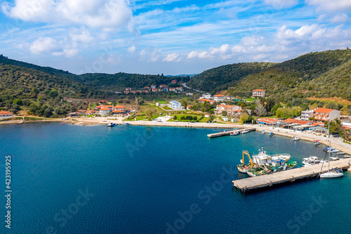 European country village on Mediterranean sea shore with coastline pier for fishing boats. Small resort town on green tree mountains summer background