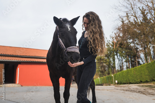 Young caucasian woman with a horse in a equestrian centre