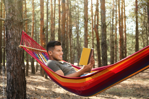Man with book relaxing in hammock outdoors on summer day © New Africa