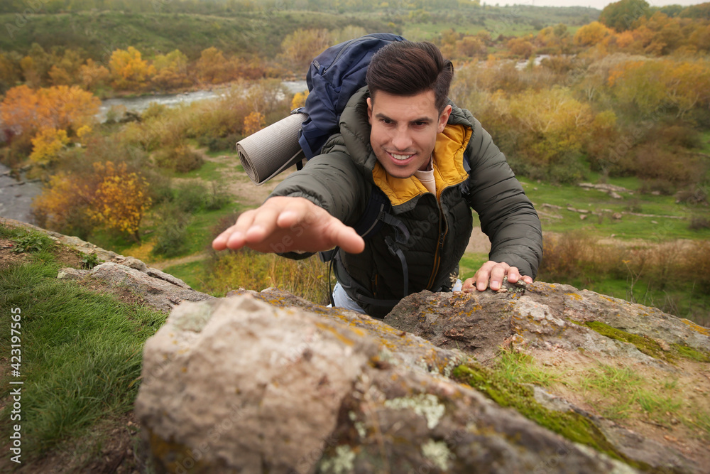 Hiker with backpack climbing up mountain on autumn day Hiker with backpack climbing up mountain on autumn day
