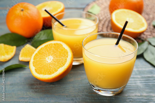 Delicious orange juice and fresh fruits on light blue wooden table, closeup