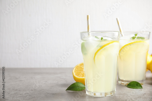 Glasses of cold lemonade on grey table. Space for text