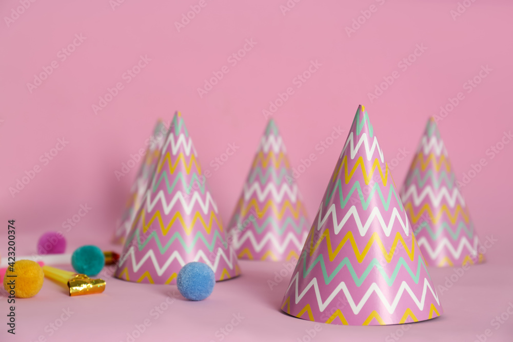 Colorful party hats, blower and fluffy balls on pink background Colorful party hats, blower and fluffy balls on pink background