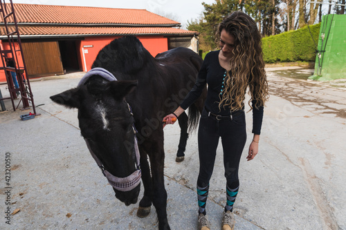 Young caucasian woman with a horse in a equestrian centre © Jorge Argazkiak