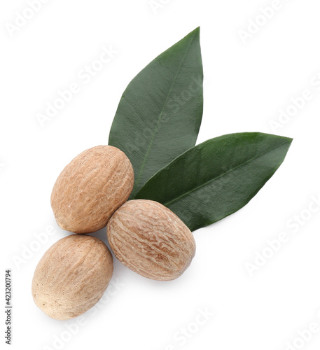 Nutmeg seeds with green leaves on white background, top view