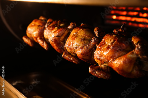 Grilling whole chickens in rotisserie machine, closeup photo
