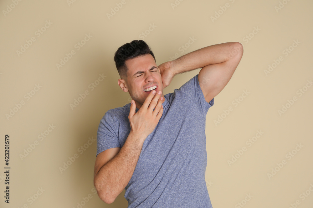 Handsome tired man yawning on beige background Handsome tired man yawning on beige background