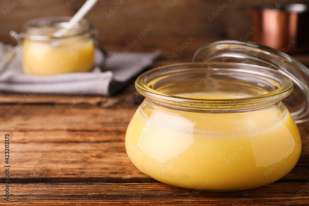 Glass jar of Ghee butter on wooden table, closeup. Space for text Glass jar of Ghee butter on wooden table, closeup. Space for text