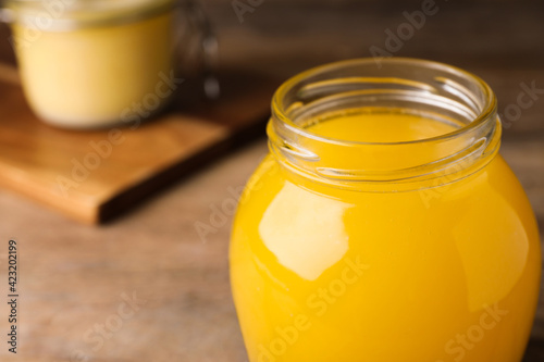 Glass jar of Ghee butter on wooden table, closeup. Space for text