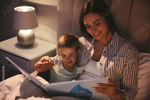 Mother reading bedtime story to her son at home photo